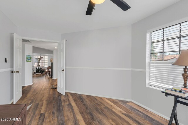 spare room featuring a ceiling fan, visible vents, baseboards, and wood finished floors