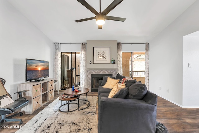 living area with a fireplace, wood finished floors, a ceiling fan, and baseboards