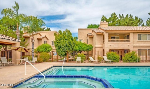 community pool featuring a patio area, fence, and a hot tub