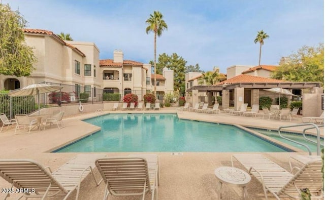 community pool with a patio area and fence