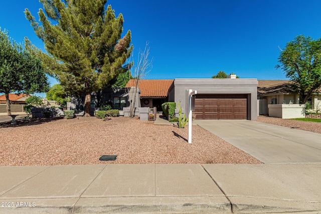 adobe home with a garage, stucco siding, and driveway
