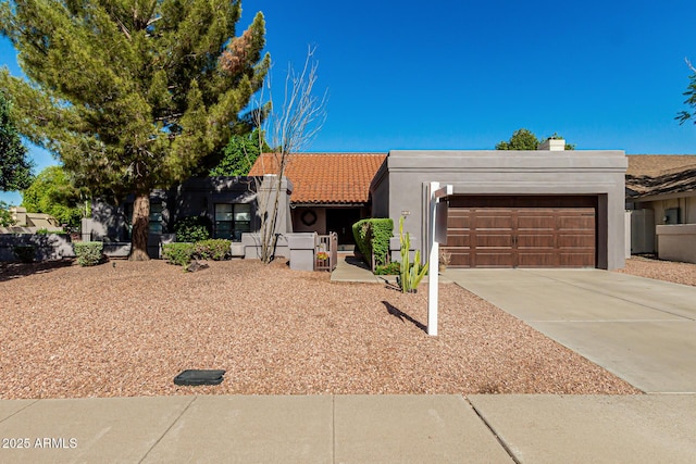 view of front of house with stucco siding, a tiled roof, driveway, and a garage