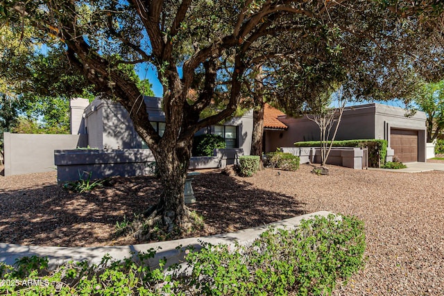 view of front of house featuring an attached garage, concrete driveway, fence private yard, and stucco siding