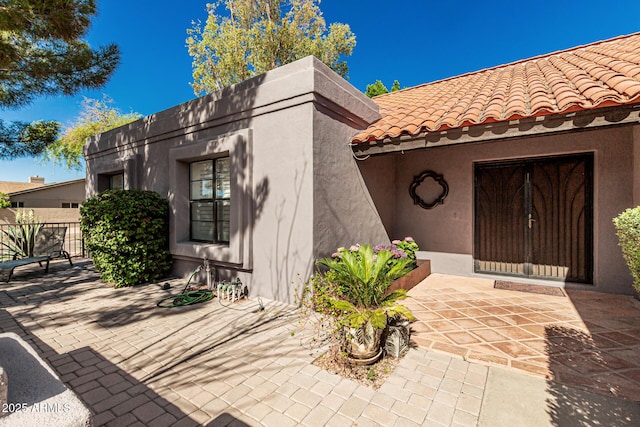 view of front of home with a patio area, stucco siding, and a tiled roof