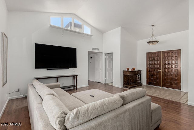 living room with high vaulted ceiling, visible vents, baseboards, and wood finished floors