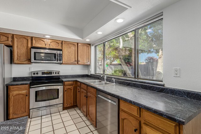 kitchen with brown cabinetry, a sink, and stainless steel appliances