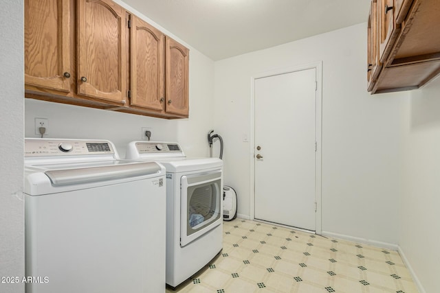 clothes washing area featuring washing machine and clothes dryer, baseboards, cabinet space, and light floors
