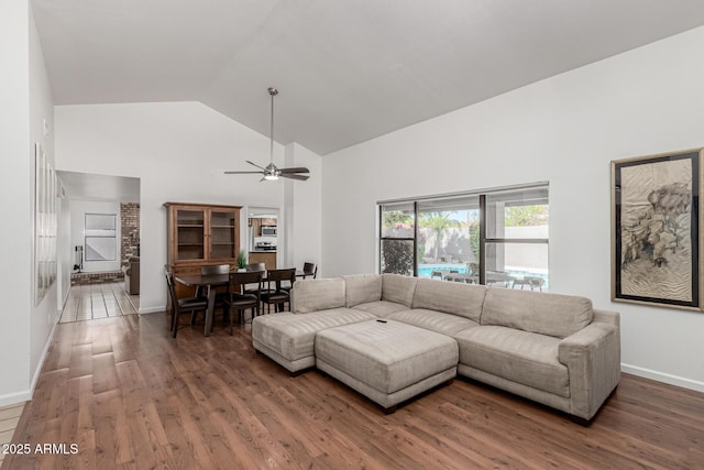 living area with high vaulted ceiling, baseboards, a ceiling fan, and wood finished floors