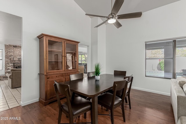 dining room featuring baseboards, a high ceiling, ceiling fan, and wood finished floors