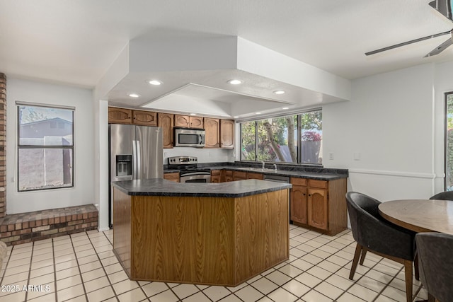 kitchen with light tile patterned floors, dark countertops, stainless steel appliances, and a sink