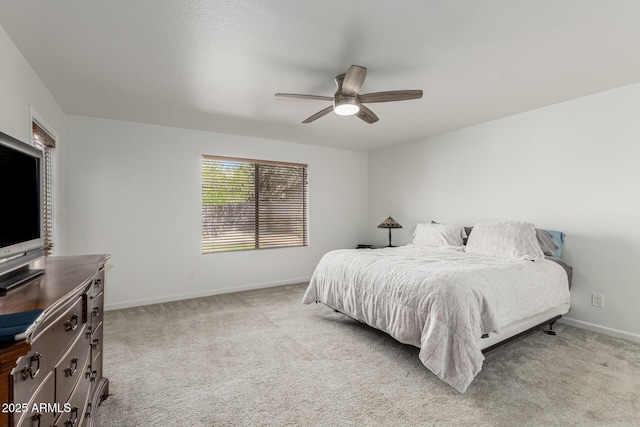 bedroom with a ceiling fan, baseboards, and light carpet
