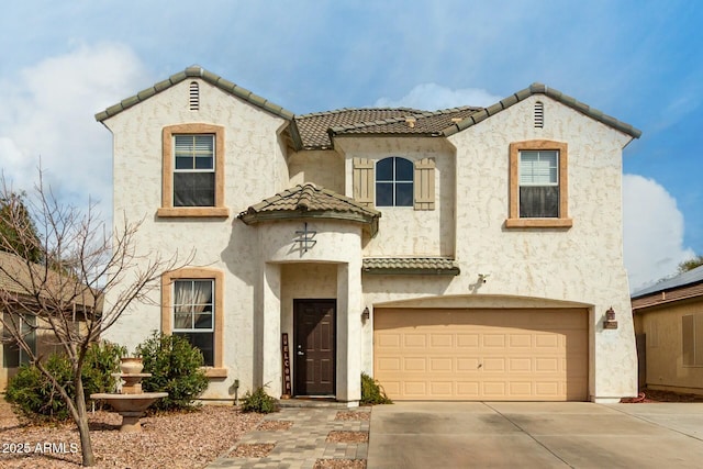 mediterranean / spanish house featuring stucco siding, driveway, an attached garage, and a tile roof