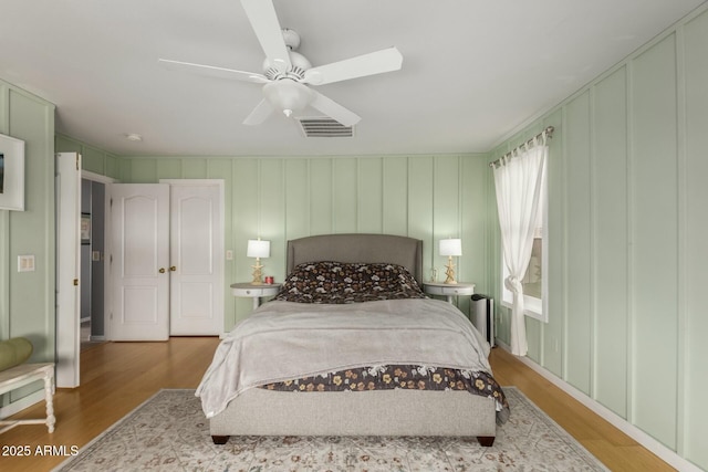 bedroom with visible vents, wood finished floors, and a ceiling fan
