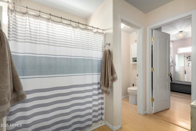 bathroom featuring baseboards, toilet, and wood finished floors