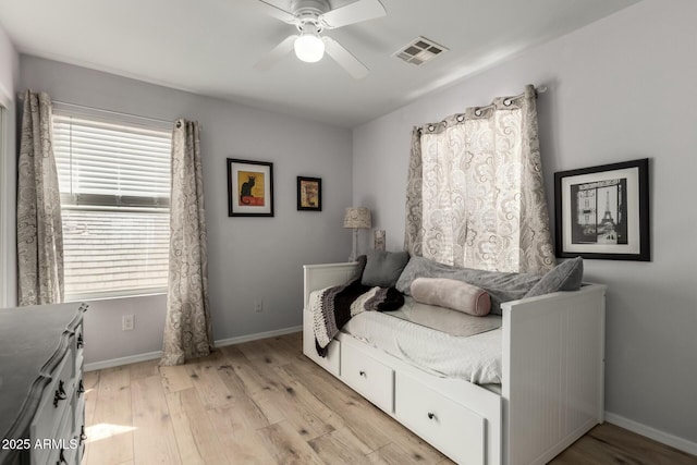 bedroom with light wood finished floors, visible vents, a ceiling fan, and baseboards