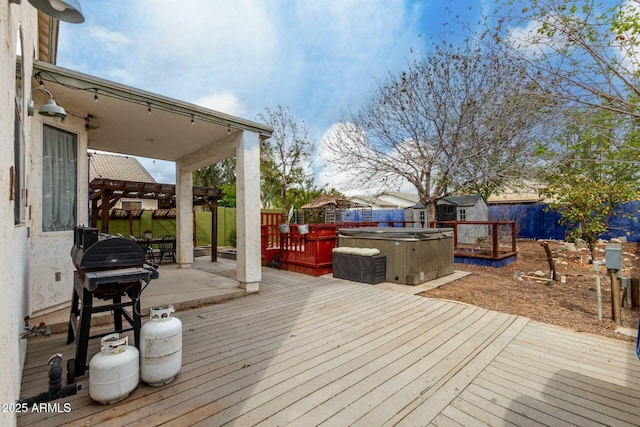 deck featuring a hot tub, a storage shed, a fenced backyard, an outdoor structure, and a grill