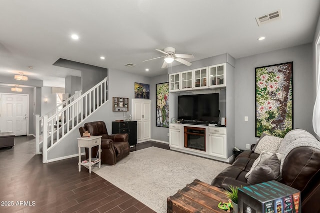 living room with recessed lighting, visible vents, dark wood-type flooring, and stairway
