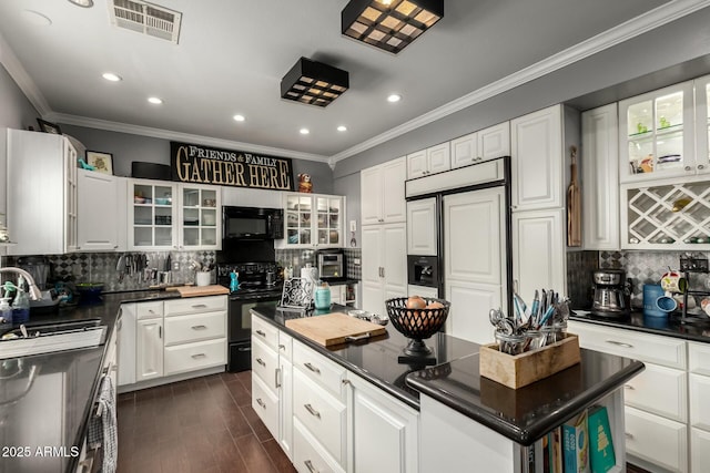 kitchen featuring dark countertops, visible vents, a kitchen island, black appliances, and a sink