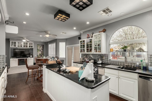 kitchen with dark countertops, visible vents, white cabinets, a ceiling fan, and stainless steel dishwasher