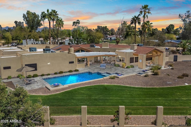 outdoor pool with a lawn, a patio area, and fence