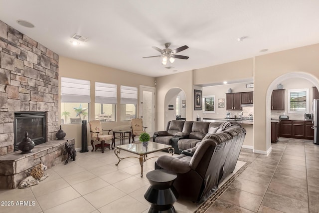 20532 W Summit Pl, Buckeye, AZ 85396 - living area featuring arched walkways, ceiling fan, light tile patterned floors, and a stone fireplace
