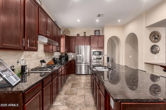 20532 W Summit Pl, Buckeye, AZ 85396 - kitchen with appliances with stainless steel finishes, under cabinet range hood, a sink, light stone finish flooring, and tasteful backsplash