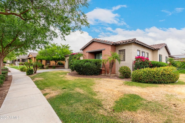 20532 W Summit Pl, Buckeye, AZ 85396 - view of front of home with a tiled roof, a front yard, stucco siding, and brick siding