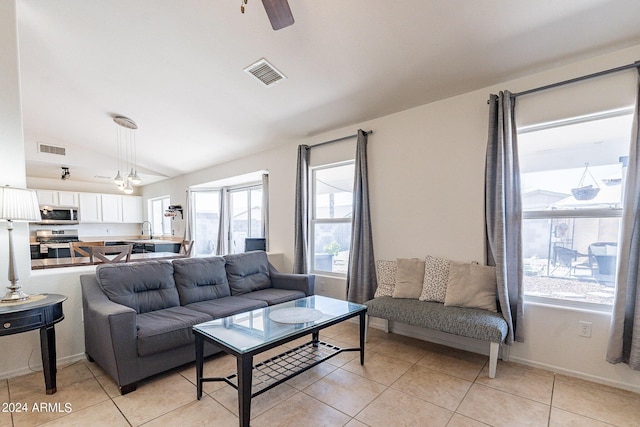 tiled living room with vaulted ceiling, ceiling fan, a healthy amount of sunlight, and sink