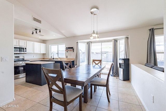 tiled dining room featuring plenty of natural light, sink, and vaulted ceiling