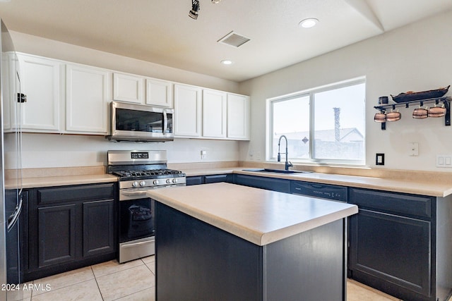 kitchen featuring sink, light tile patterned floors, appliances with stainless steel finishes, a kitchen island, and white cabinets