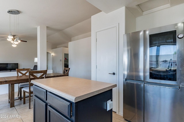 kitchen featuring light tile patterned flooring, a kitchen island, stainless steel fridge, and ceiling fan