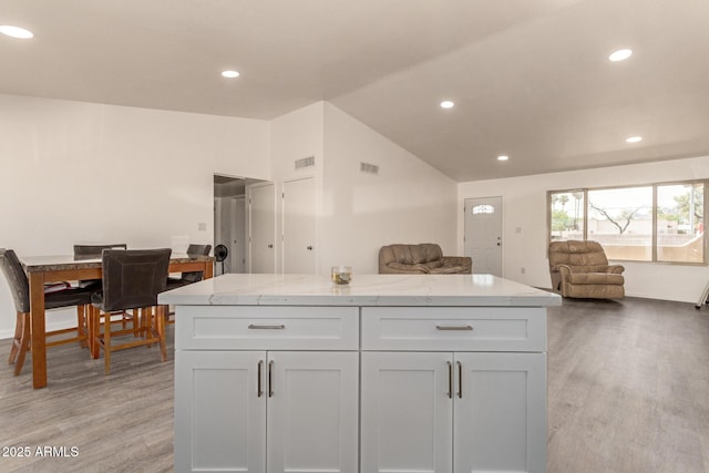 2826 E Cactus Rd, Phoenix, AZ 85032 - kitchen featuring open floor plan, light wood-style flooring, white cabinets, light stone countertops, and vaulted ceiling
