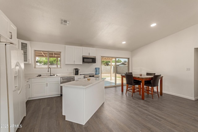 2826 E Cactus Rd, Phoenix, AZ 85032 - kitchen featuring appliances with stainless steel finishes, light countertops, dark wood finished floors, a kitchen island, and white cabinetry