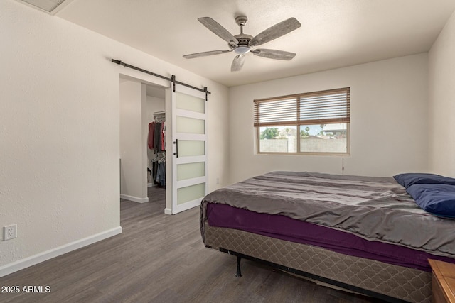 2826 E Cactus Rd, Phoenix, AZ 85032 - bedroom featuring wood finished floors, a spacious closet, a barn door, a ceiling fan, and a closet