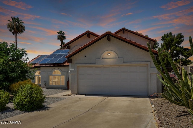 7108 W Morrow Dr, Glendale, AZ 85308 - mediterranean / spanish-style house with a tiled roof, driveway, a garage, roof mounted solar panels, and stucco siding