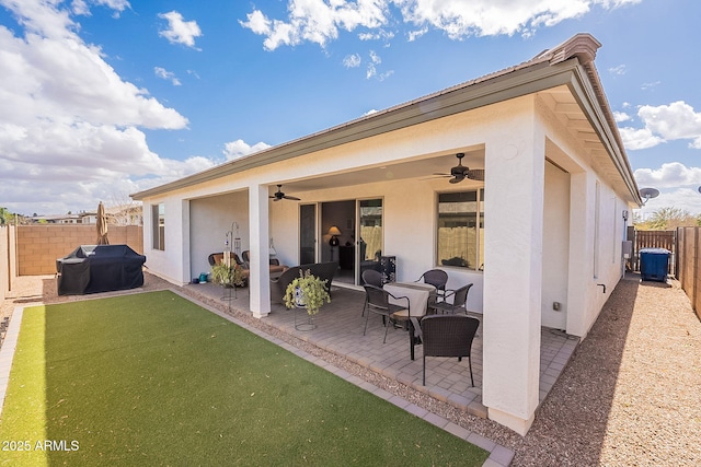 rear view of house with ceiling fan, a patio, a fenced backyard, and stucco siding