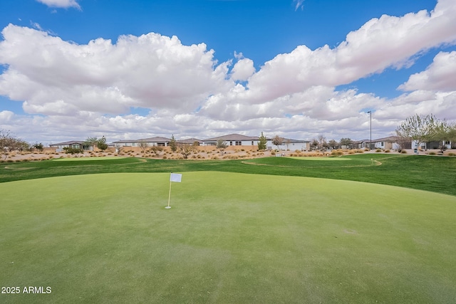 view of property's community featuring view of golf course and a lawn