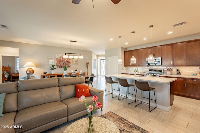 living area with ceiling fan, wood finish floors, visible vents, and recessed lighting