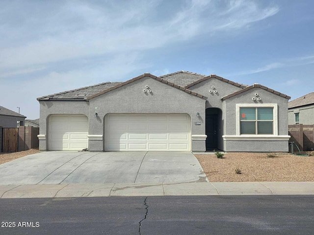 mediterranean / spanish home featuring an attached garage, fence, concrete driveway, and stucco siding