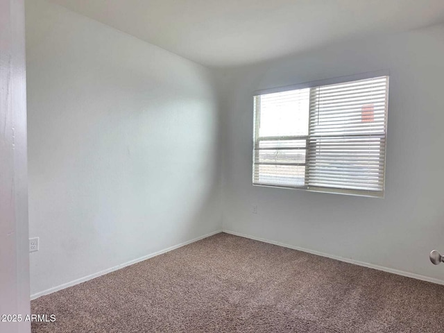 carpeted spare room featuring baseboards