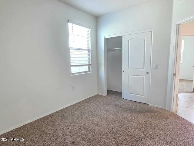 unfurnished bedroom with a closet, baseboards, and carpet flooring