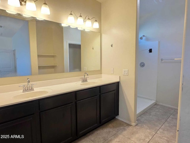 full bath with double vanity, walk in shower, a sink, and tile patterned floors