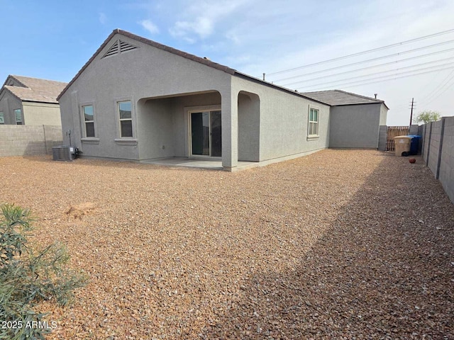 rear view of house featuring a patio area, a fenced backyard, central AC, and stucco siding