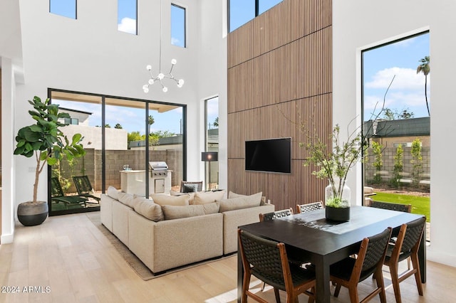 living room featuring plenty of natural light, a notable chandelier, light hardwood / wood-style floors, and a high ceiling