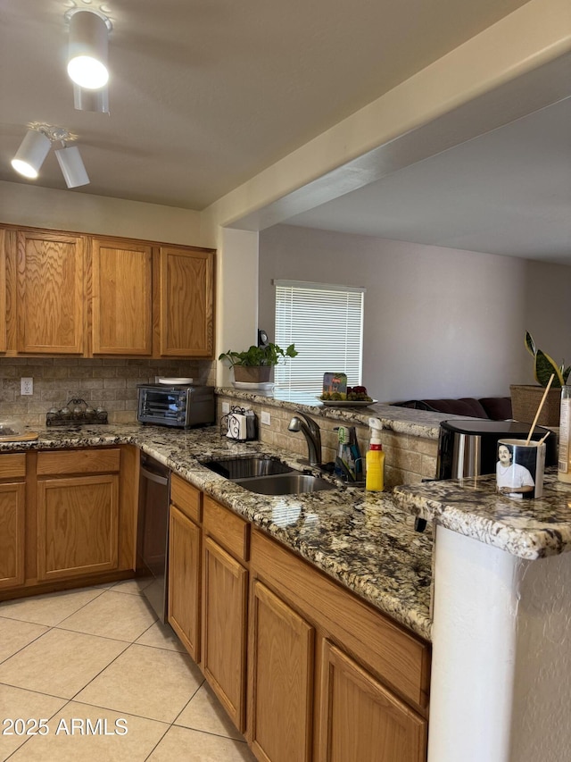 kitchen with decorative backsplash, dishwasher, a peninsula, a sink, and light tile patterned flooring