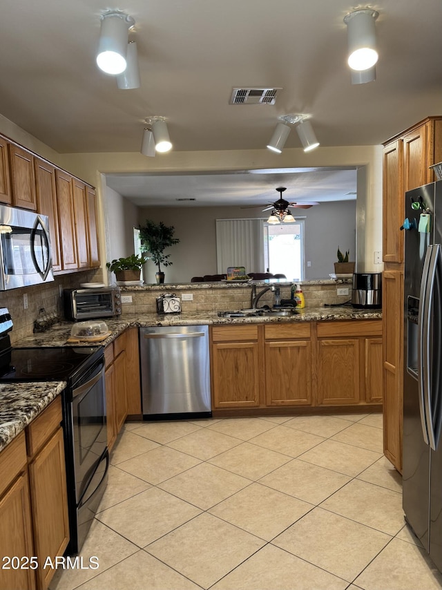 kitchen featuring black appliances, brown cabinetry, and a sink