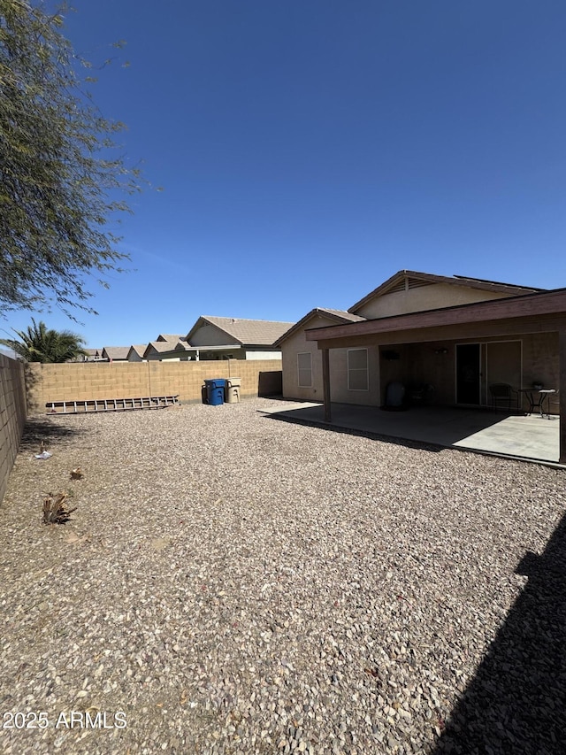 rear view of house with a fenced backyard and a patio