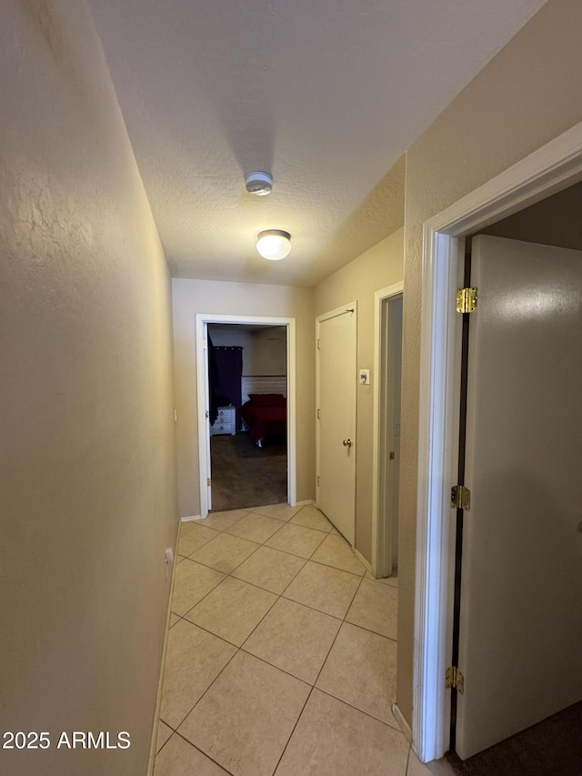 corridor with a textured ceiling and light tile patterned floors