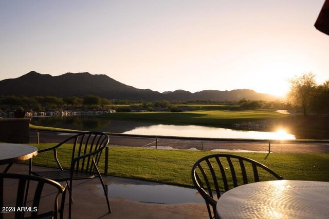 patio terrace at dusk with a water and mountain view and a yard