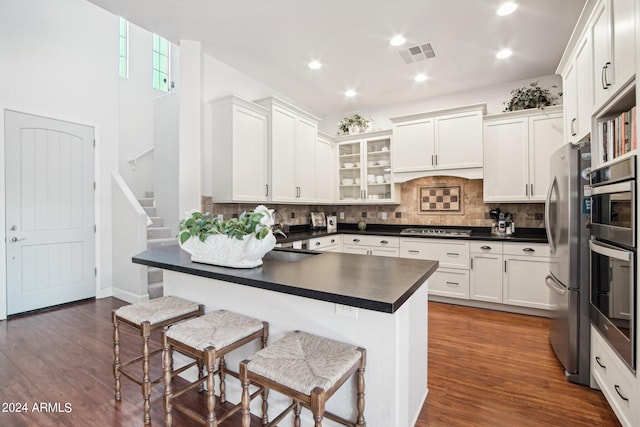 kitchen with white cabinets, stainless steel appliances, dark hardwood / wood-style flooring, and a breakfast bar